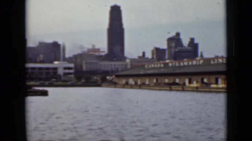 1940 Ontario harbor view with open water in the foreground, a Canada Steamship Lines wharf, and downtown buildings beyond.