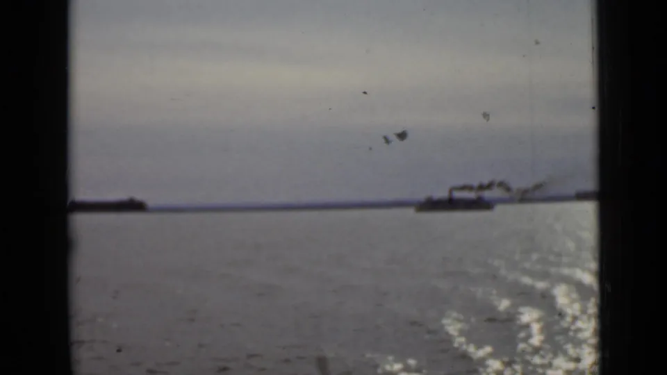 1940 Ontario 8mm view of a distant steam vessel on open water, seen through dark film-frame edges.