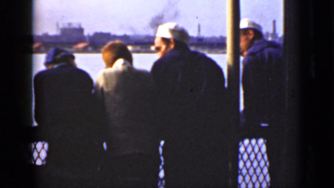 In 1940s Ontario home-movie footage, four men in coats and hats stand by a bridge railing above a river, facing an industrial cityscape.