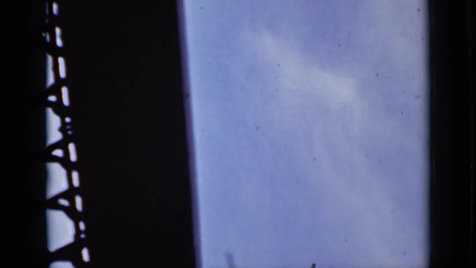 1940 Ontario 8mm frame showing pale blue sky, faint cloud, and a dark metal or window-side structure at the left edge.