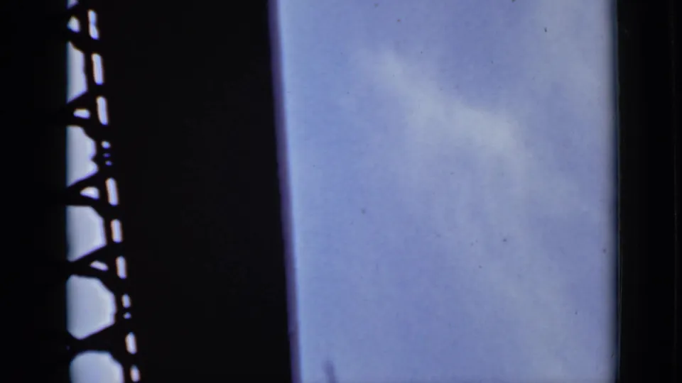 1940 Ontario 8mm frame of pale blue sky and faint cloud, bordered by a dark vertical structural strip at left.