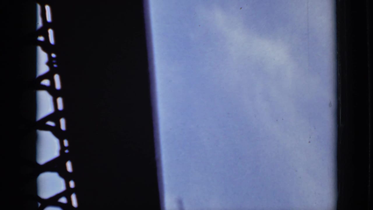 Dark silhouetted structure beside pale sky and water from a moving boat.