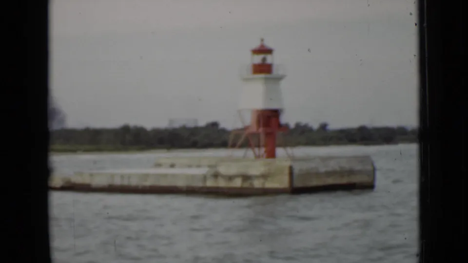 Final 1940 Ontario frame showing the red-and-white pier light receding along a concrete breakwater under an overcast sky.