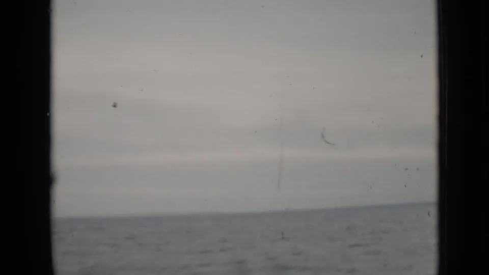 1940 Ontario 8mm frame looking from a moving boat toward open gray water and a low horizon after the lighthouse leaves view.