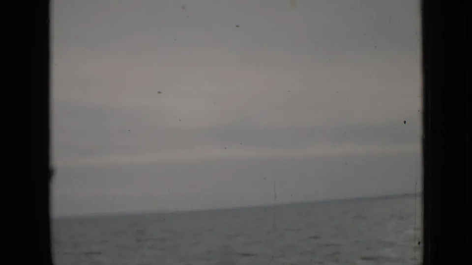 1940 Ontario 8mm frame of open lake water under a cloudy sky, with the home-movie gate edge and surface wear visible.