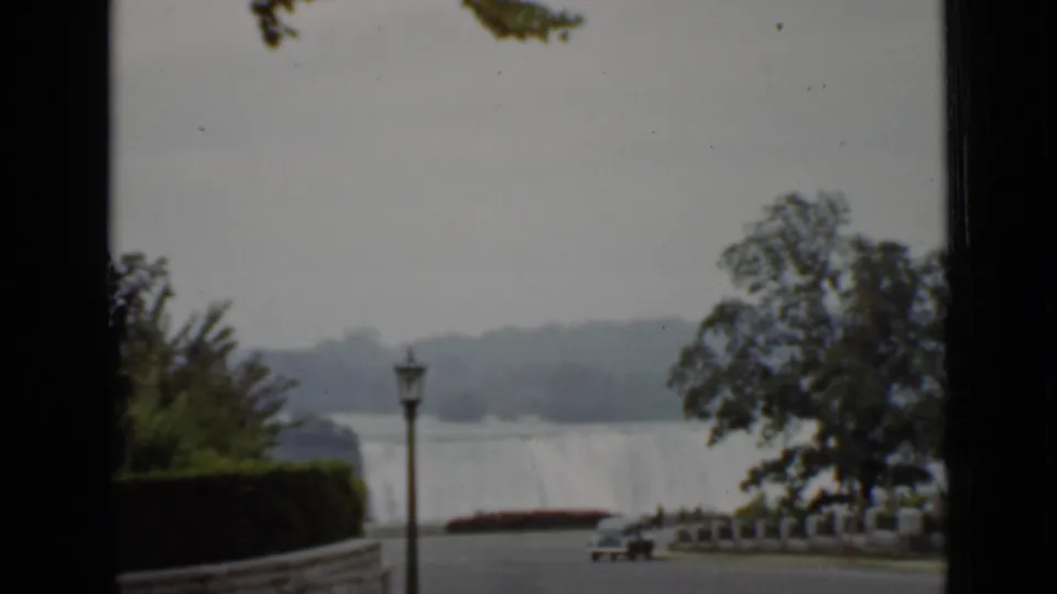 1940 Ontario travel frame showing a distant waterfall-like view, trees, a lamppost, and a riverside or overlook foreground.