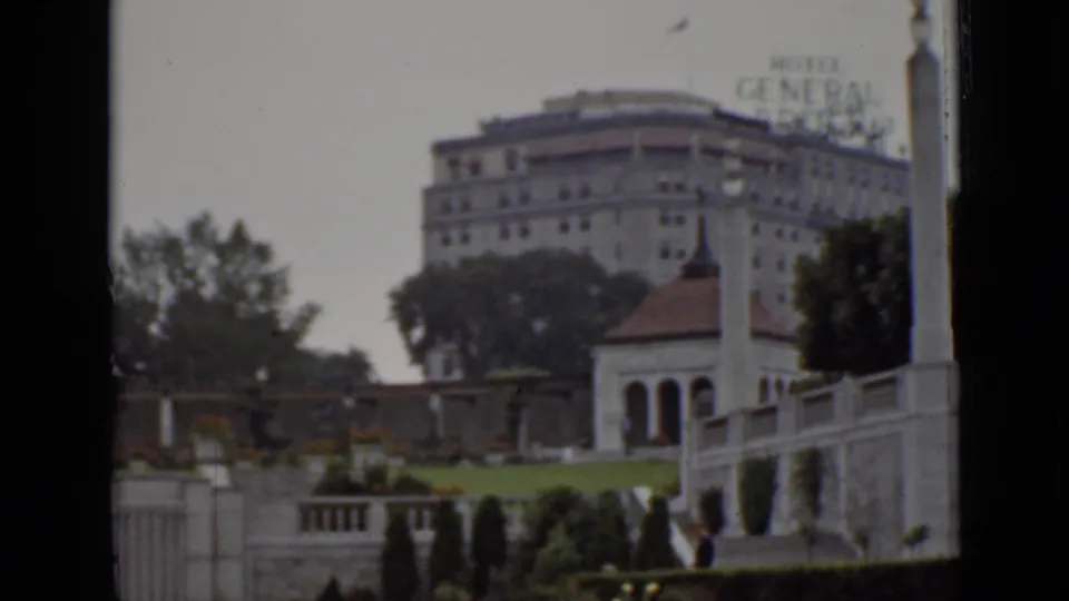 Hotel General Brock exterior in Ontario with its rooftop sign, formal gardens, stone staircases, railings, and trees.