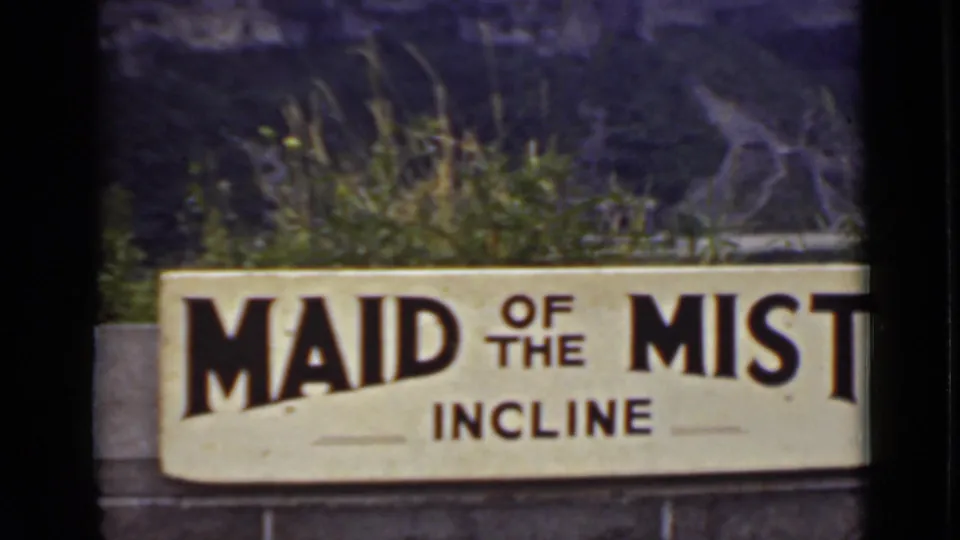 Close view of a Maid of the Mist Incline sign, with plants and stone structures behind it in the Ontario travel footage.