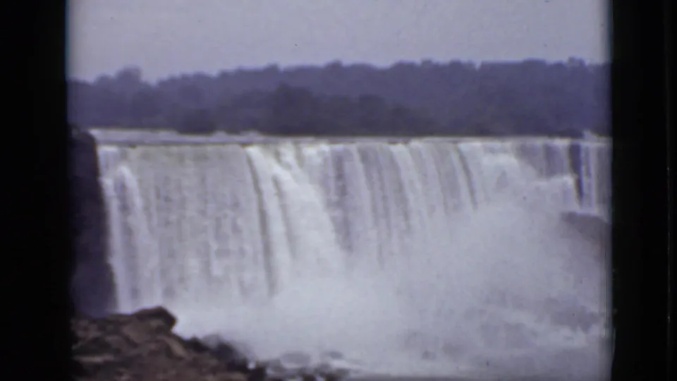 American Falls at Niagara Falls, viewed from the Ontario side in 1940 8mm footage, with mist rising below distant trees.