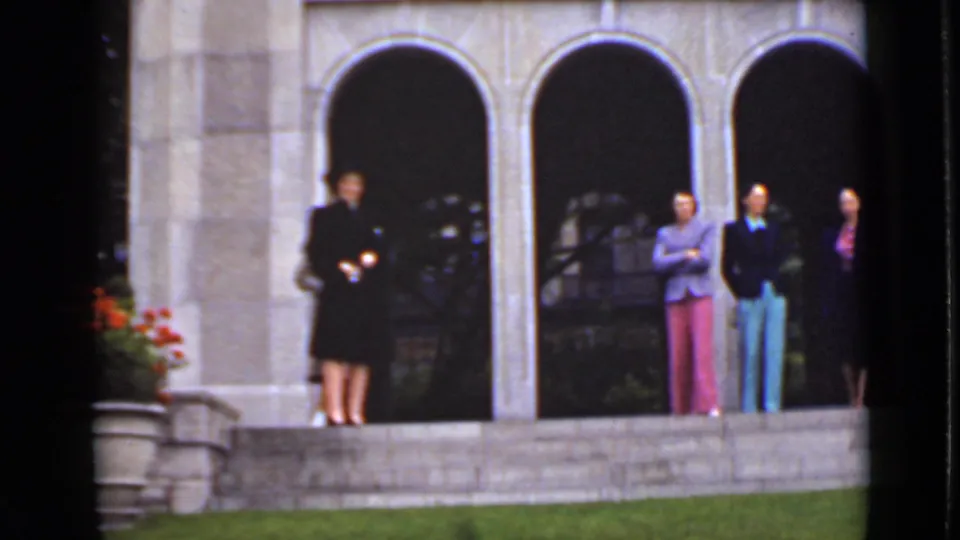 Women in mid-century formal clothing stand spaced along stone steps outside an Ontario building with dark arched recesses.