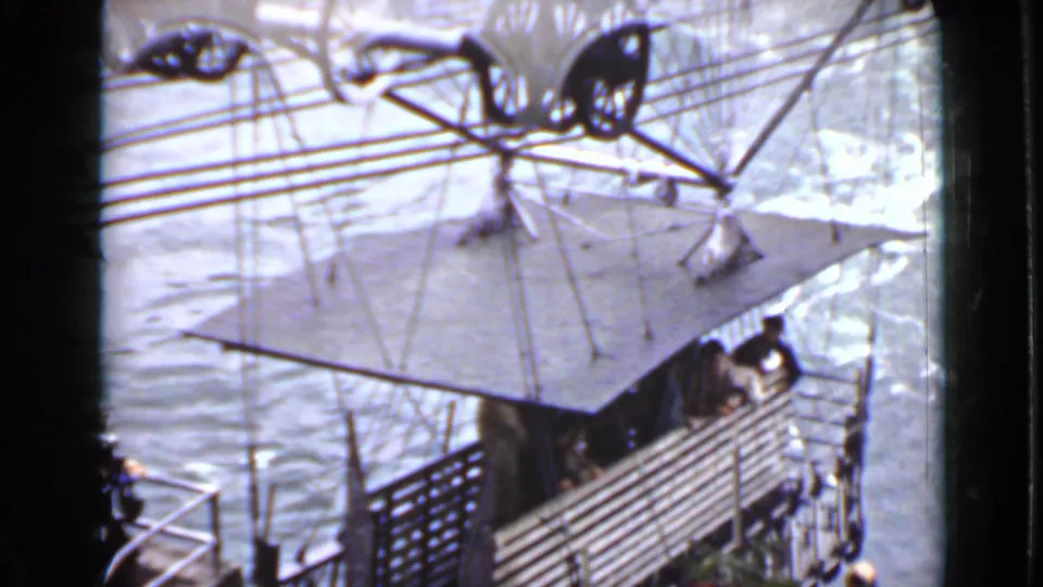 Ontario home-movie frame showing water beside a cable-and-wheel structure, with a platform and railing visible.