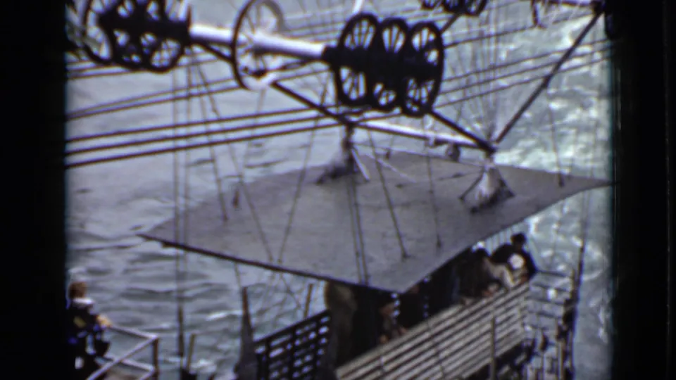 1940 Ontario home-movie frame showing passengers in an open suspended cable gondola above rough river water.