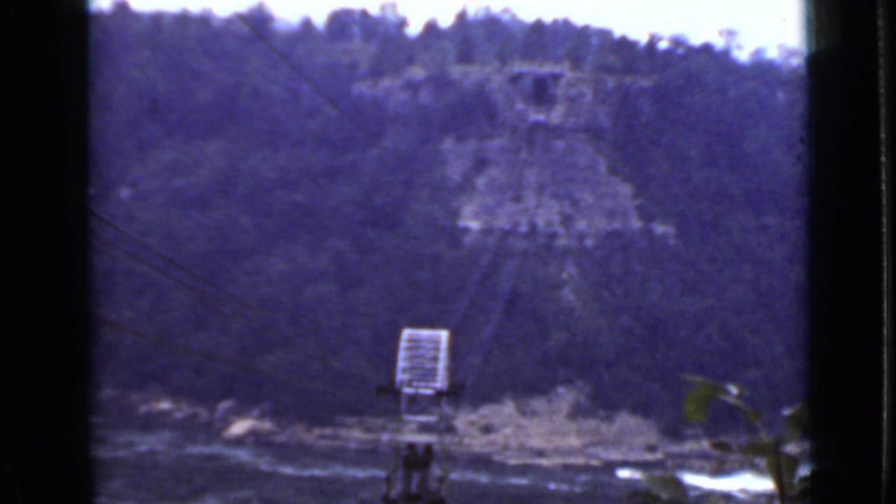 Forested river valley with utility pole and overhead wires in the foreground.