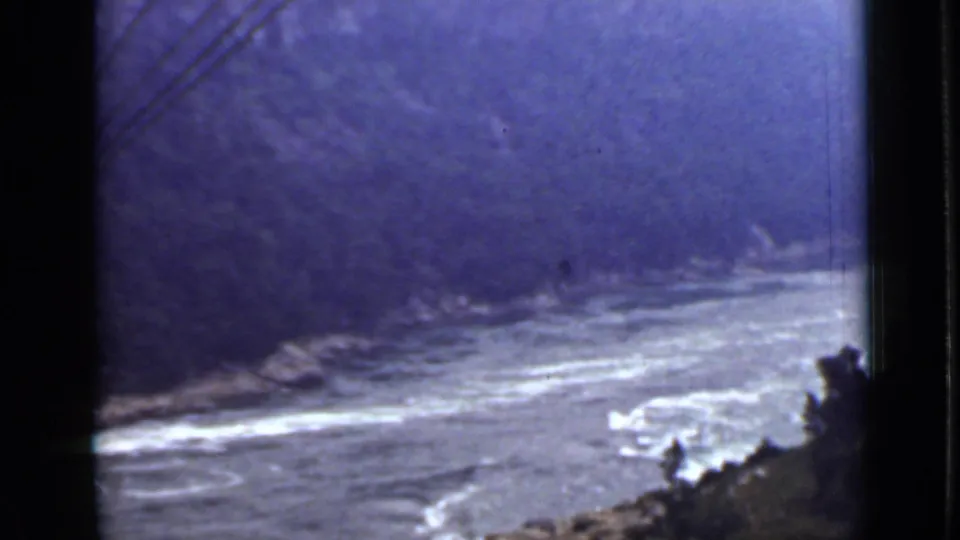 1940 Ontario 8mm frame showing a river bend, white-water patches, rocky banks, and wooded slopes in soft focus.