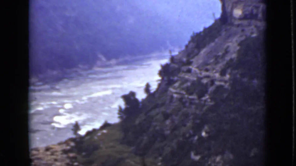 1940 Ontario 8mm frame of a broad river gorge with pale water, rugged slopes, vegetation, and visible film grain.