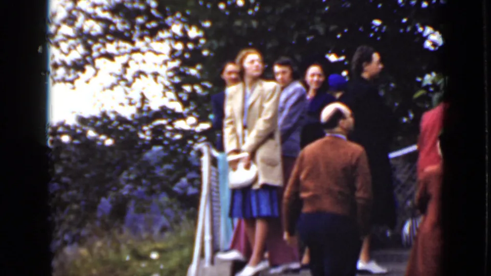 1940 Ontario 8mm frame showing several visitors in coats and skirts near a lookout railing with trees and water beyond.