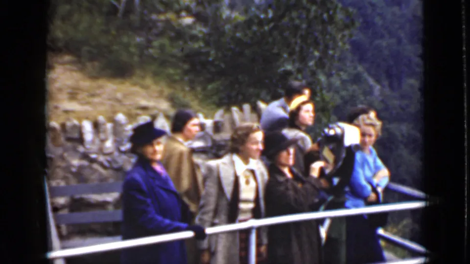 At an outdoor Ontario viewpoint, adults in coats and hats stand by a railing, and one visitor appears to use a camera.