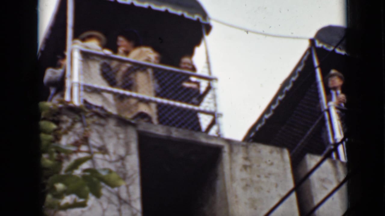 Visitors stand on a covered observation deck above a rocky waterside area.