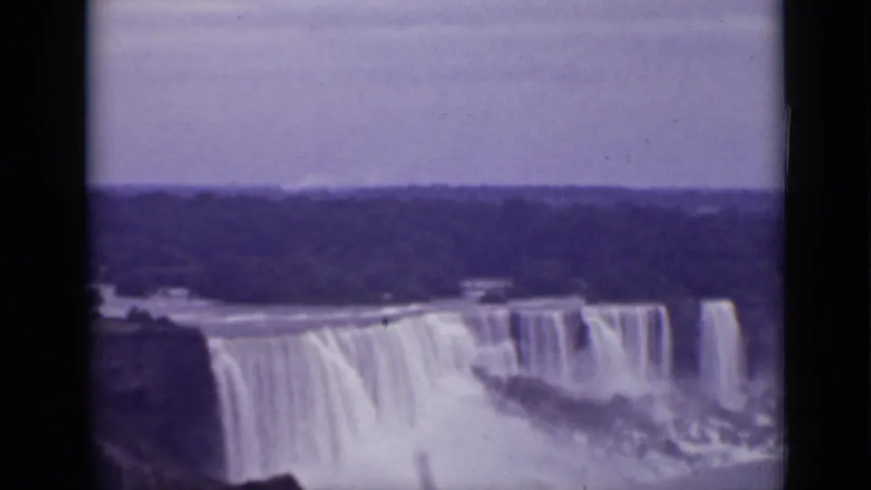 1940 Ontario home-movie frame of Niagara Falls, showing several broad curtains of water under a muted sky with film-frame borders.