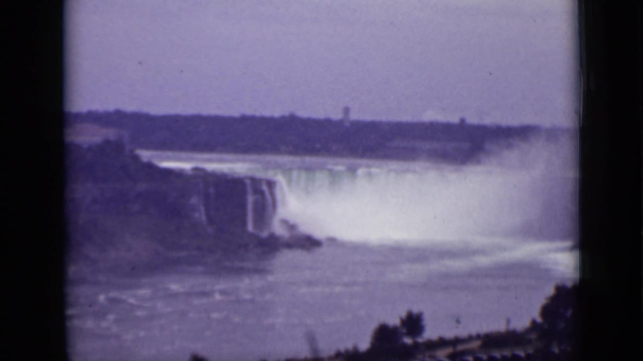 Wide view of Niagara Falls with mist rising over the river.