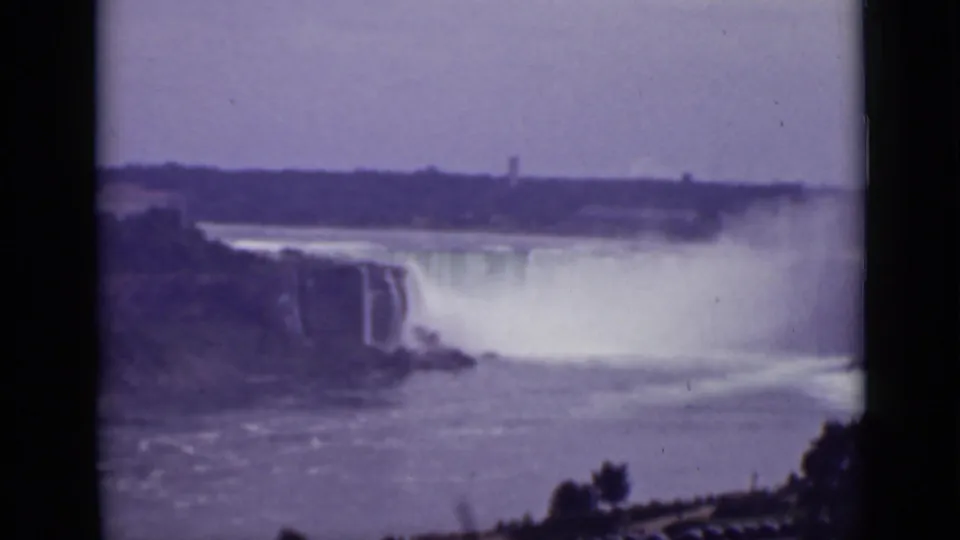 1940 Ontario view of Niagara Falls, showing the cataract, dense spray, turbulent water, and distant shoreline structures.