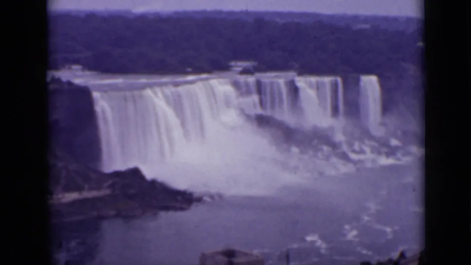 1940 Ontario 8mm frame emphasizing Horseshoe Falls and mist, with river water and a partial overlook structure at the lower edge.