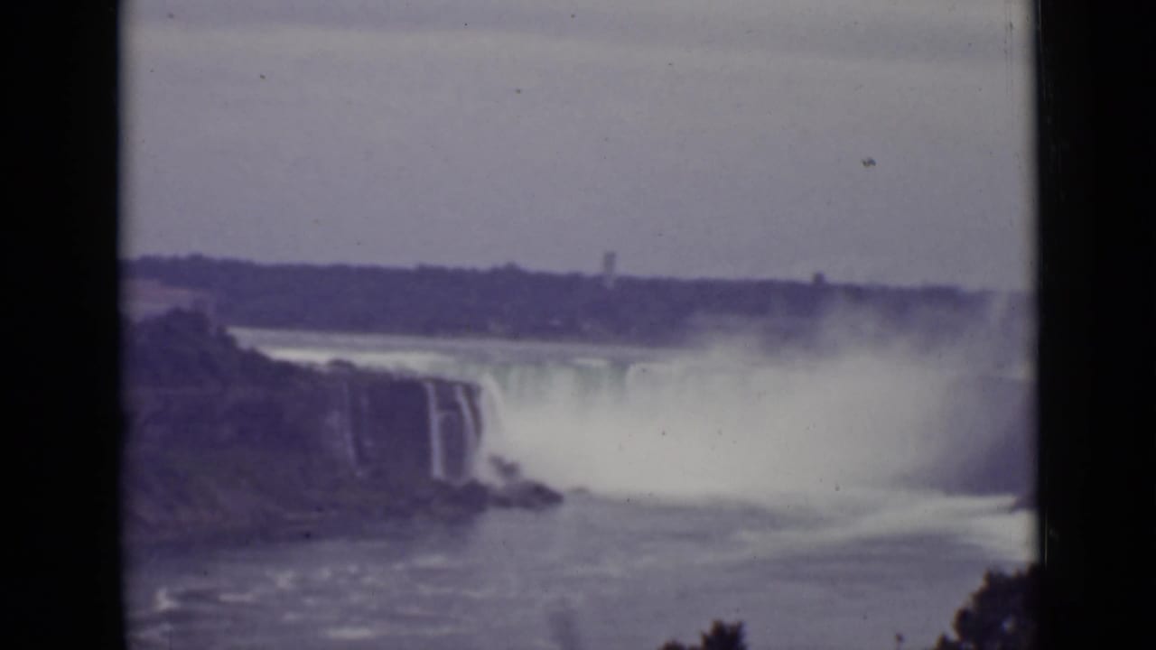 Distant view of Niagara Falls with mist rising over the river.