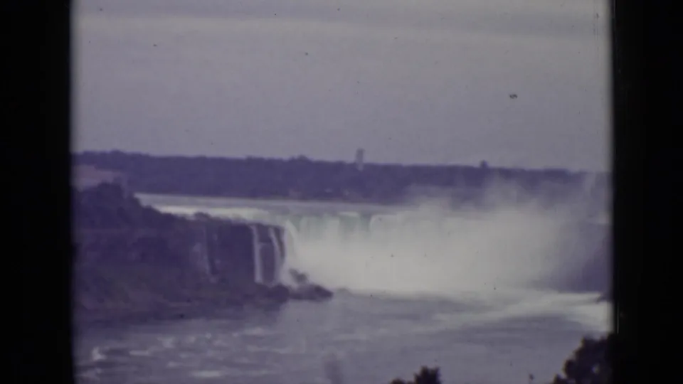 1940 Ontario 8mm frame showing Niagara Falls from a high vantage point, with mist drifting above the river and dark film edges visible.