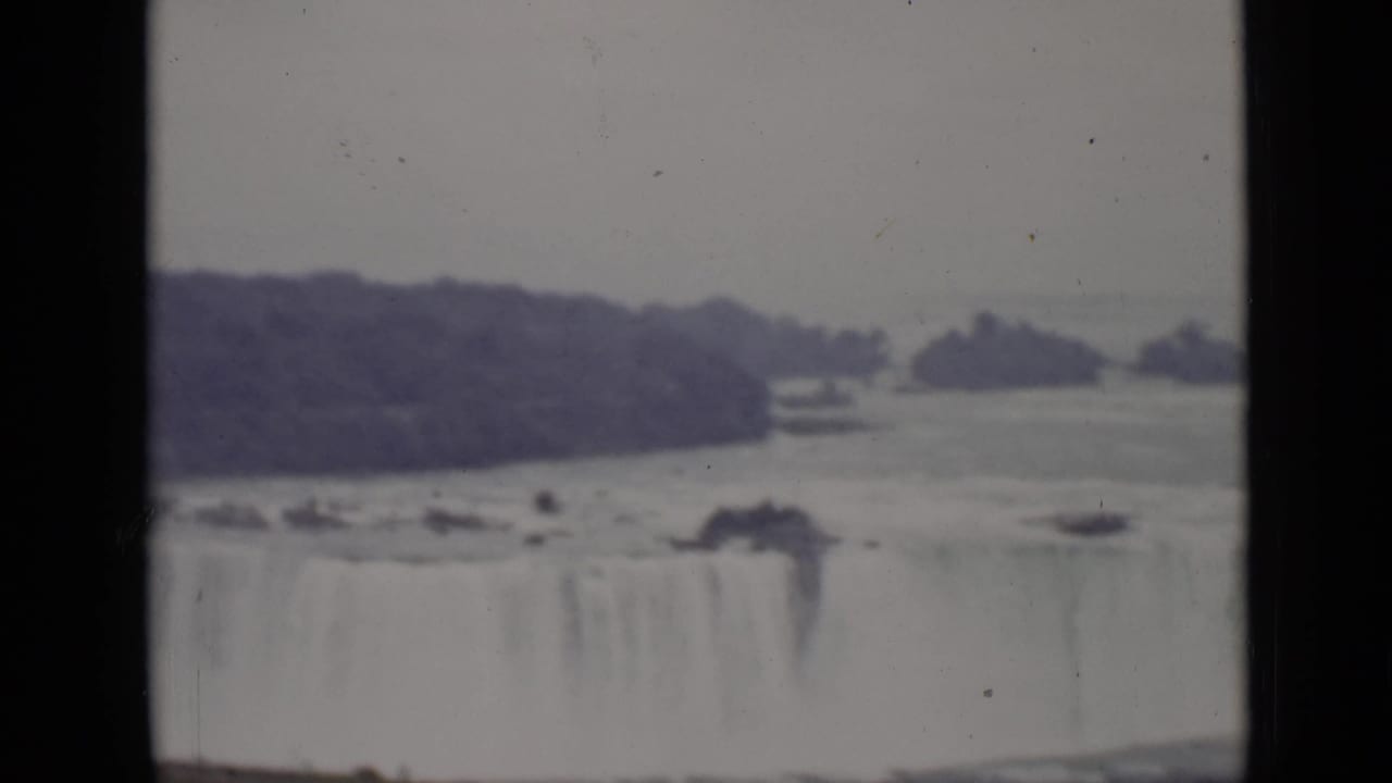 Horseshoe Falls seen across the river with islands and mist beyond the brink.