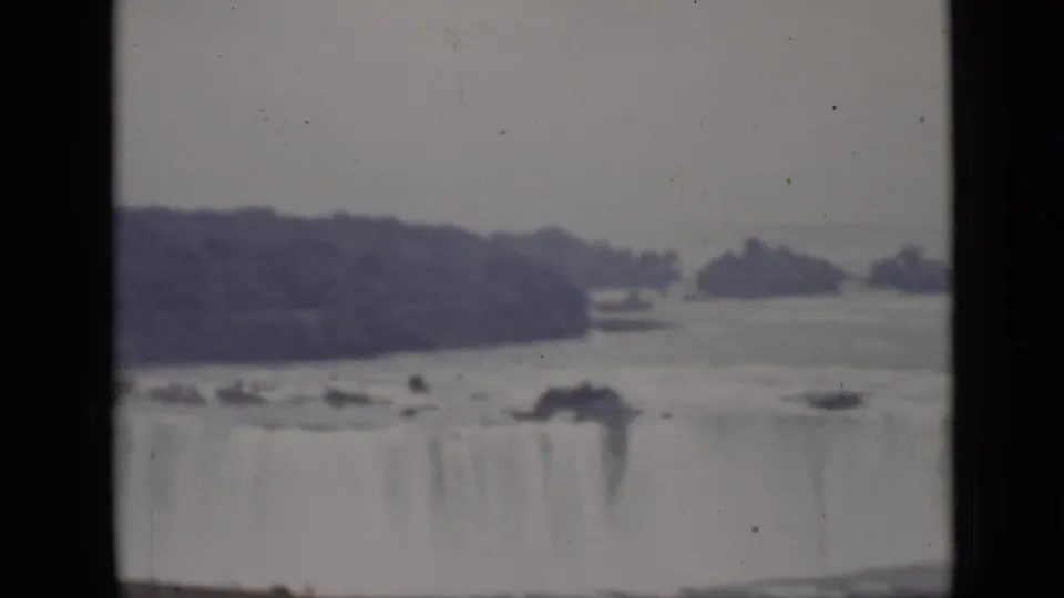 1940 8mm view from Ontario showing Horseshoe Falls, distant tree-covered islands, pale rushing water, and black film-frame borders.