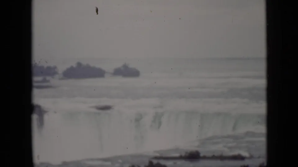 Faded 8mm frame of Horseshoe Falls in Ontario, with mist rising from the cascade and low islands across the upper river.