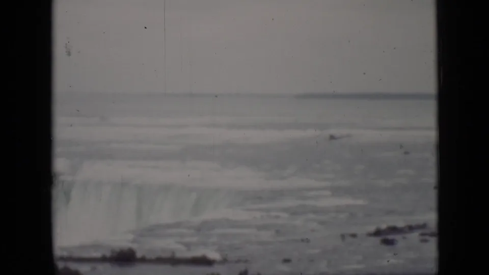 1940 Ontario home-movie frame showing a wide stretch of river and the Niagara Falls rim through soft, scratched 8mm film.