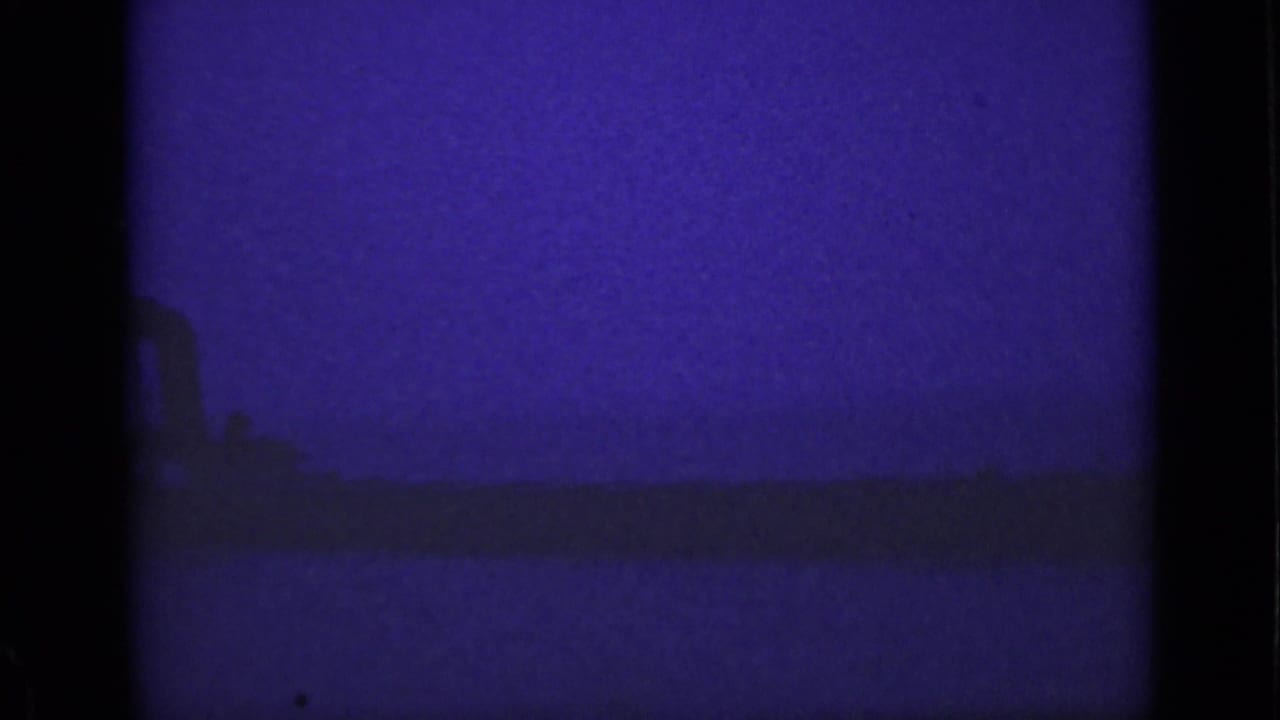 Dark water and a faint ship silhouette under a purple-blue night sky.
