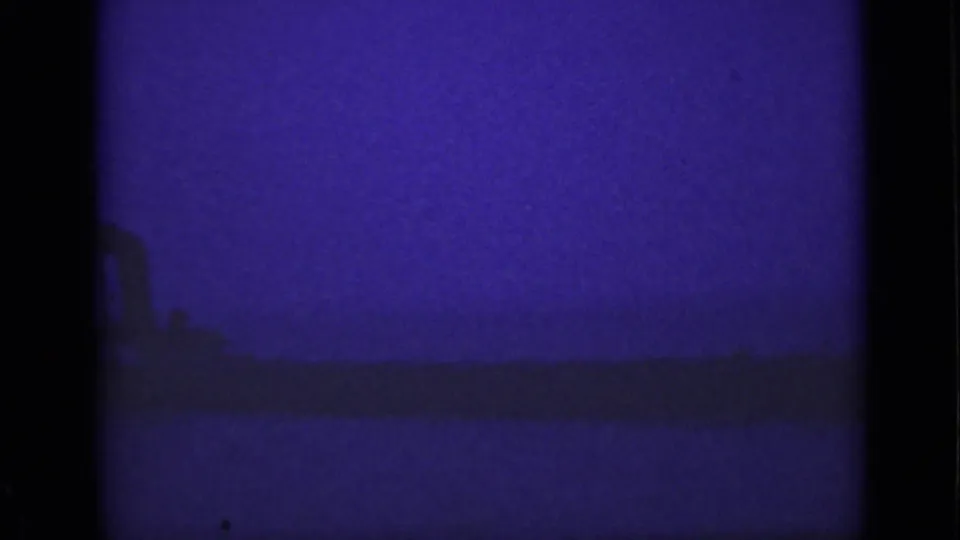 1940 Ontario 8mm frame with a dim vessel silhouette near the waterline in purple-blue low light.