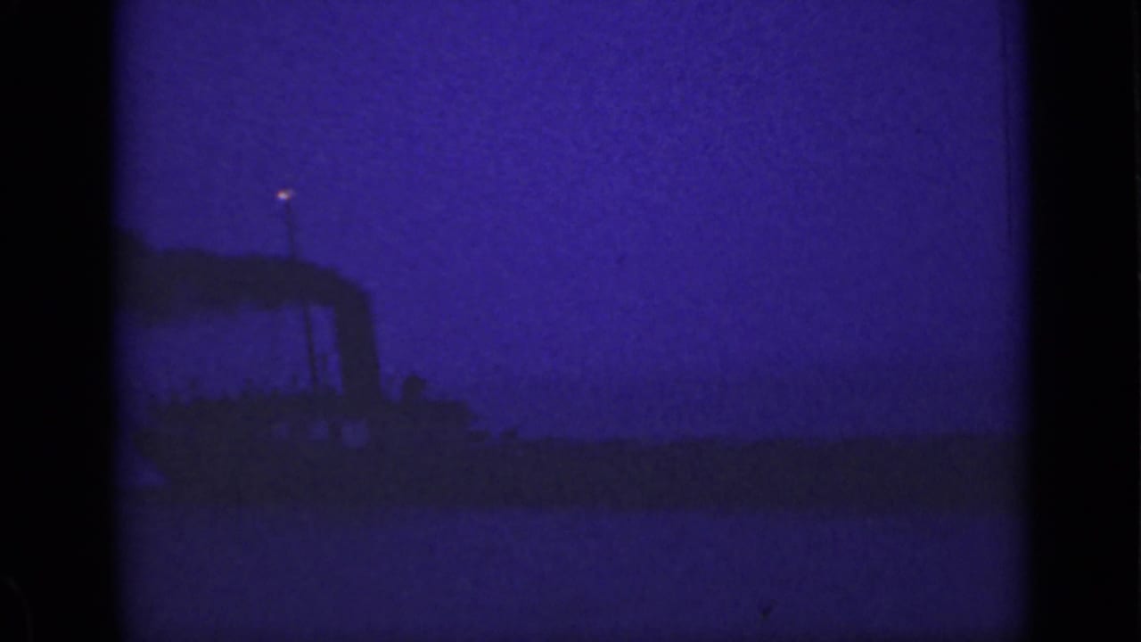Silhouetted vessel with smoke and a small light in the night sky.