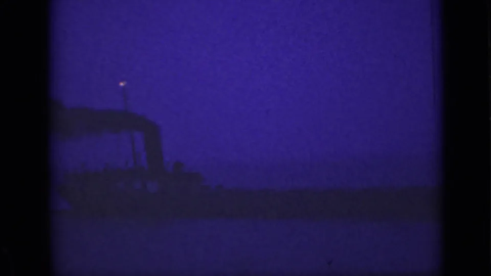 1940 Ontario 8mm frame showing a dark ship shape, smoke plume, and small glowing mast light at night.