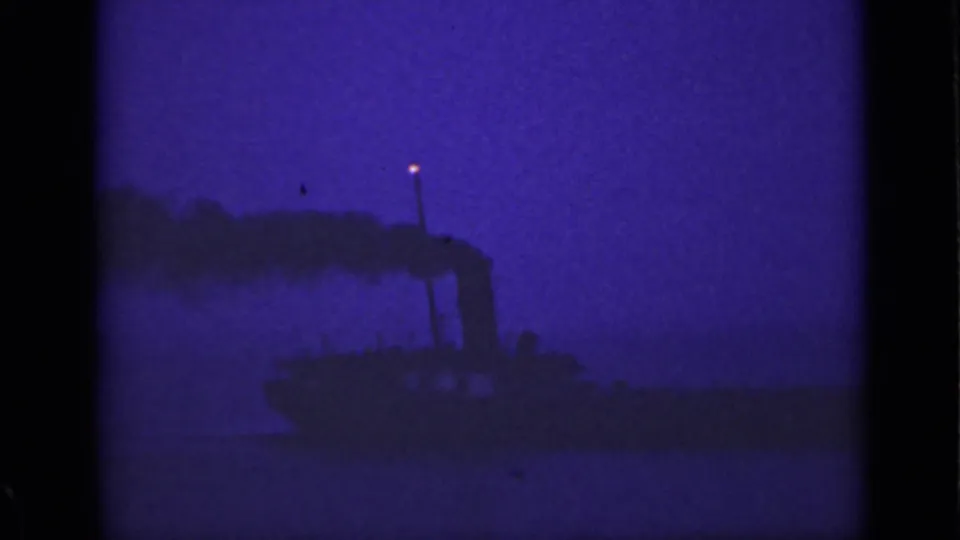 1940 Ontario home-movie frame with a dark vessel, stack smoke, and low-light purple-blue film cast.