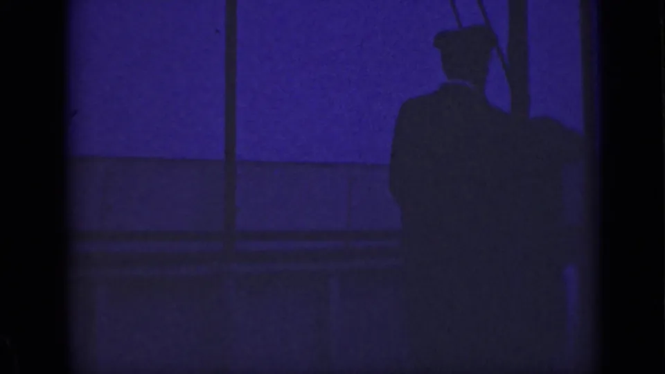 1940 Ontario boat-deck view showing a shadowed adult figure near railings, with low-light water visible beyond.