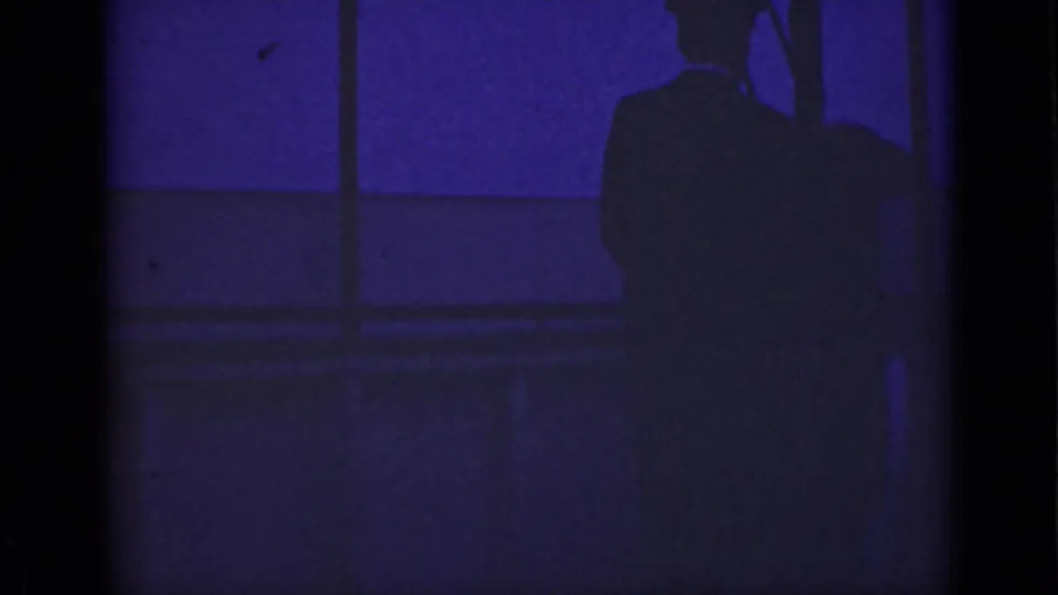 1940 Ontario 8mm frame showing a backlit adult man near a waterfront bridge or railing, tinted deep blue-purple.
