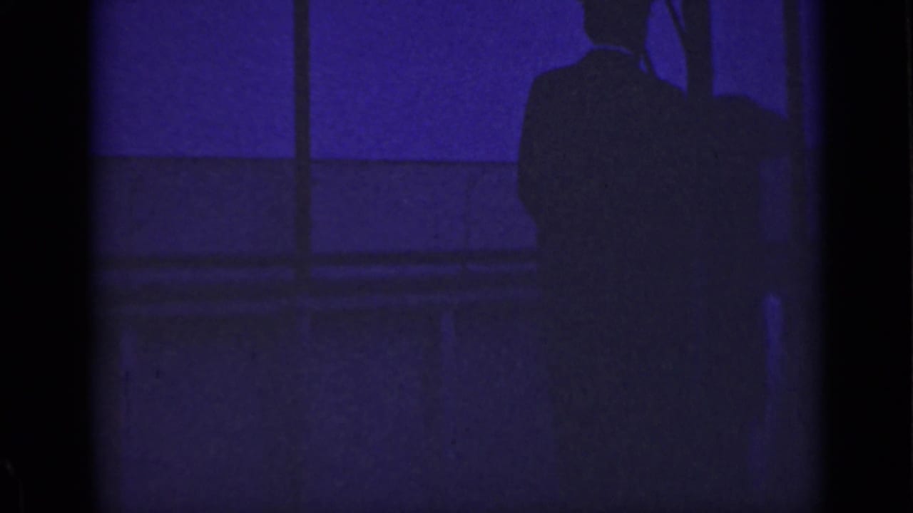 A shadowed man stands at the right edge beside vertical bridge or railing elements.