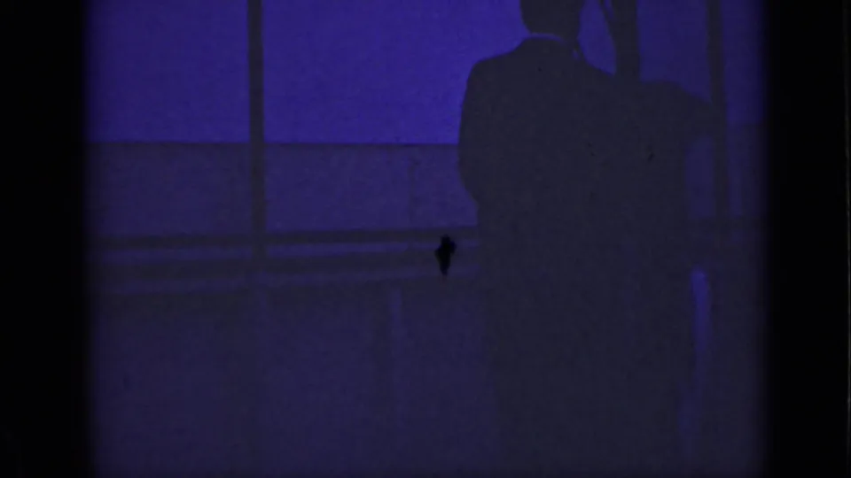 1940 Ontario home-movie frame with a mostly still man-shaped silhouette beside a window in dark purple light.