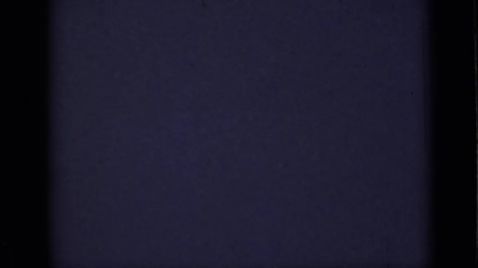 1940 Ontario 8mm frame where the person is mostly obscured, leaving a dim wall, window edge, and purple shadow.