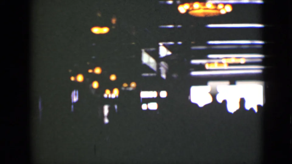 Dim Ontario interior from the 1940s reel, with blurred overhead lights and silhouetted figures near a bright window or doorway.