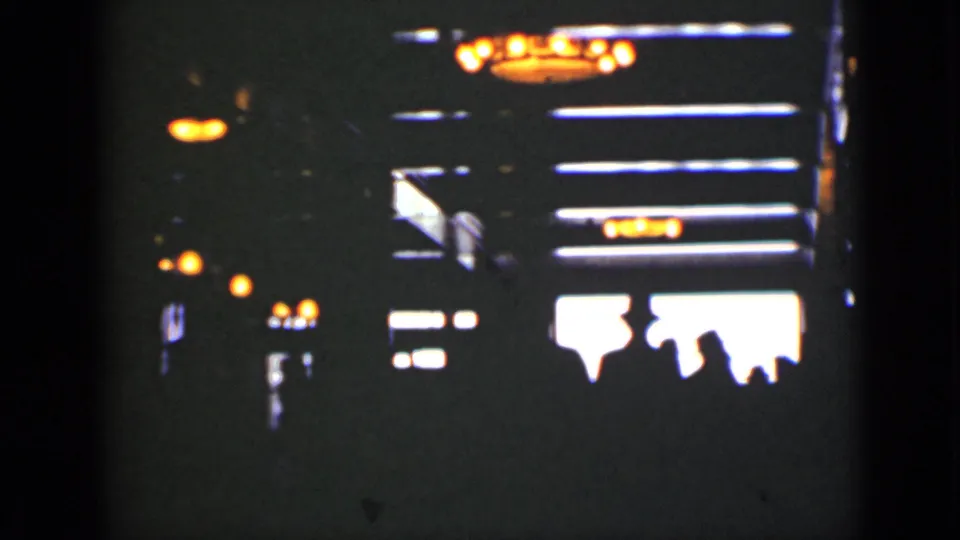 Soft 8mm view of a dark Ontario entertainment interior, with bright fixtures and people silhouetted against a luminous opening.