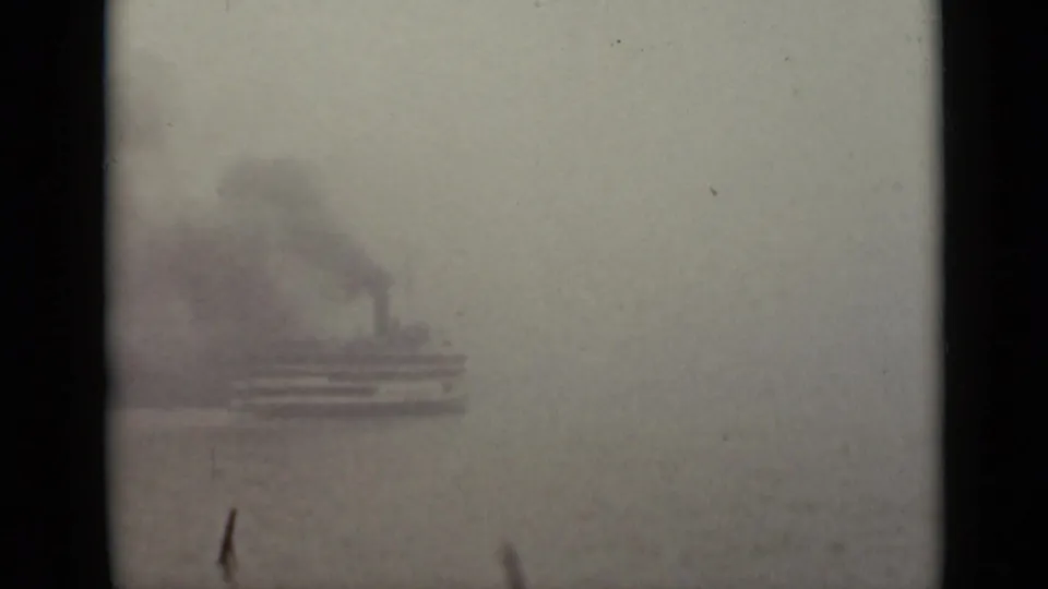 Soft 8mm view from Ontario in 1940 showing a steam-like vessel partly obscured by fog beyond a dark window frame.