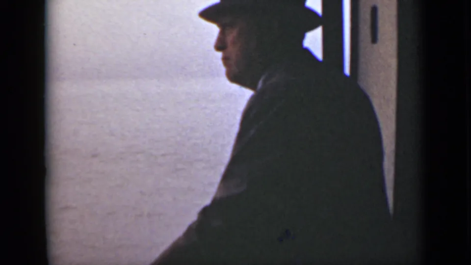 The final frame holds on the man's shadowed profile beside the boat opening, with bright water beyond the cabin edge.