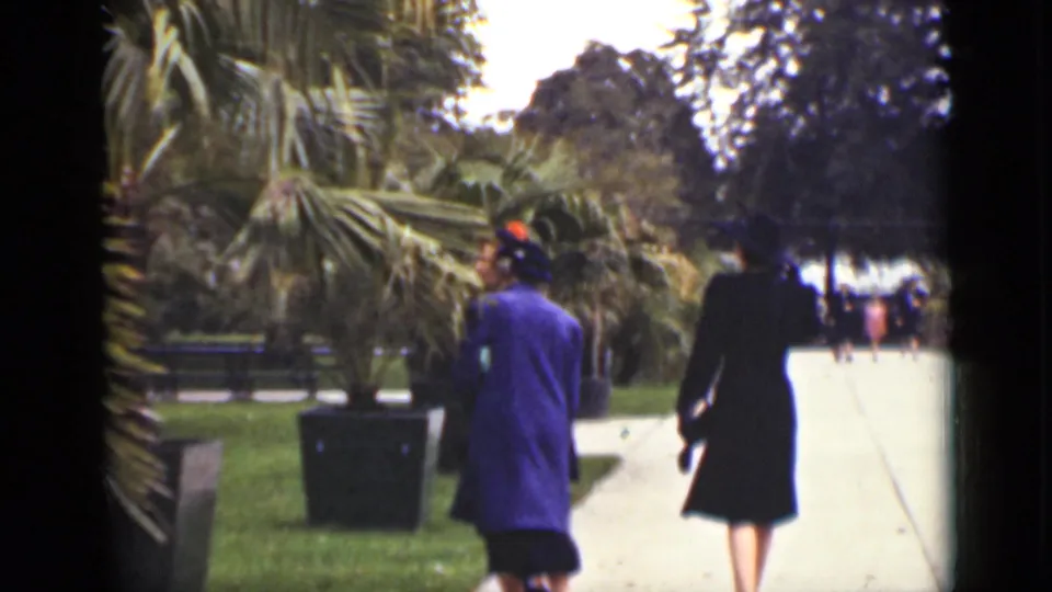 1940 Ontario home-movie frame of women in dark and blue coats walking through a landscaped public square.