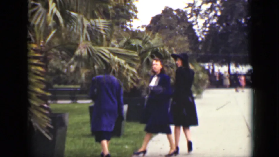 Women in period coats and hats stand near a path in a landscaped Ontario square, filmed on 8mm in 1940.