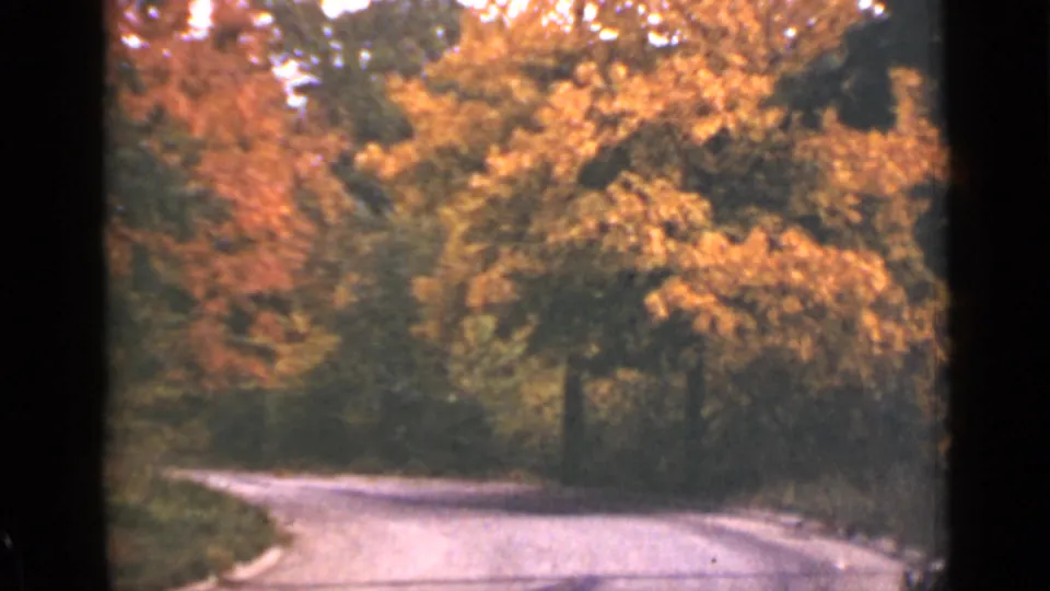 1940 Ontario 8mm frame showing a quiet curving country road under dense orange and yellow autumn trees.