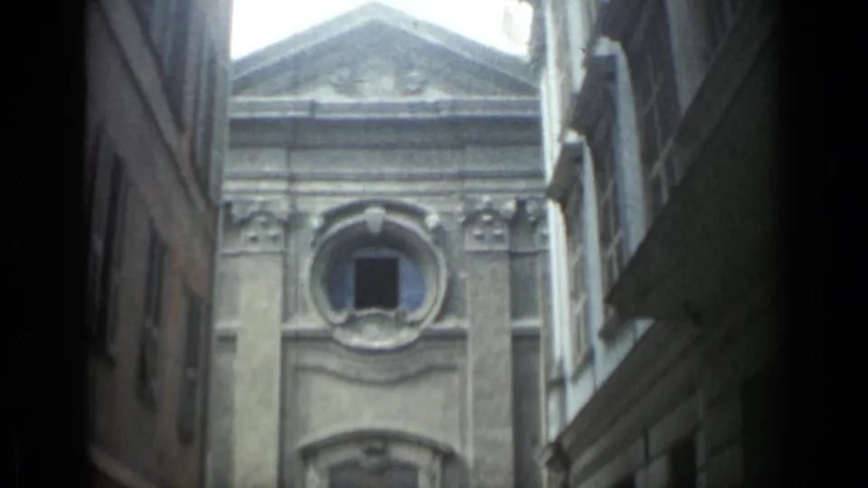 Upward Cannes street view showing the ornate upper facade, oculus window, pediment edge, and bright sky.